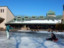 遊びグループで、氷を使った遊びができないか凍った広場の上で滑って遊びを考案している職員の様子の写真